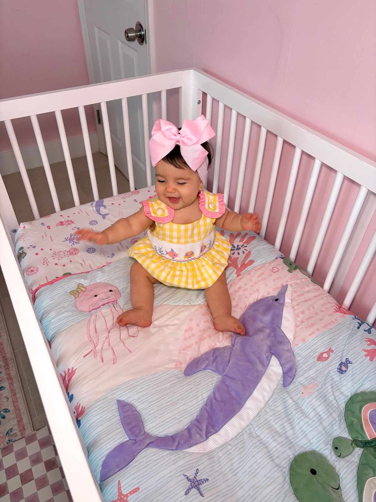 Baby in crib on pink under the sea crib bedding