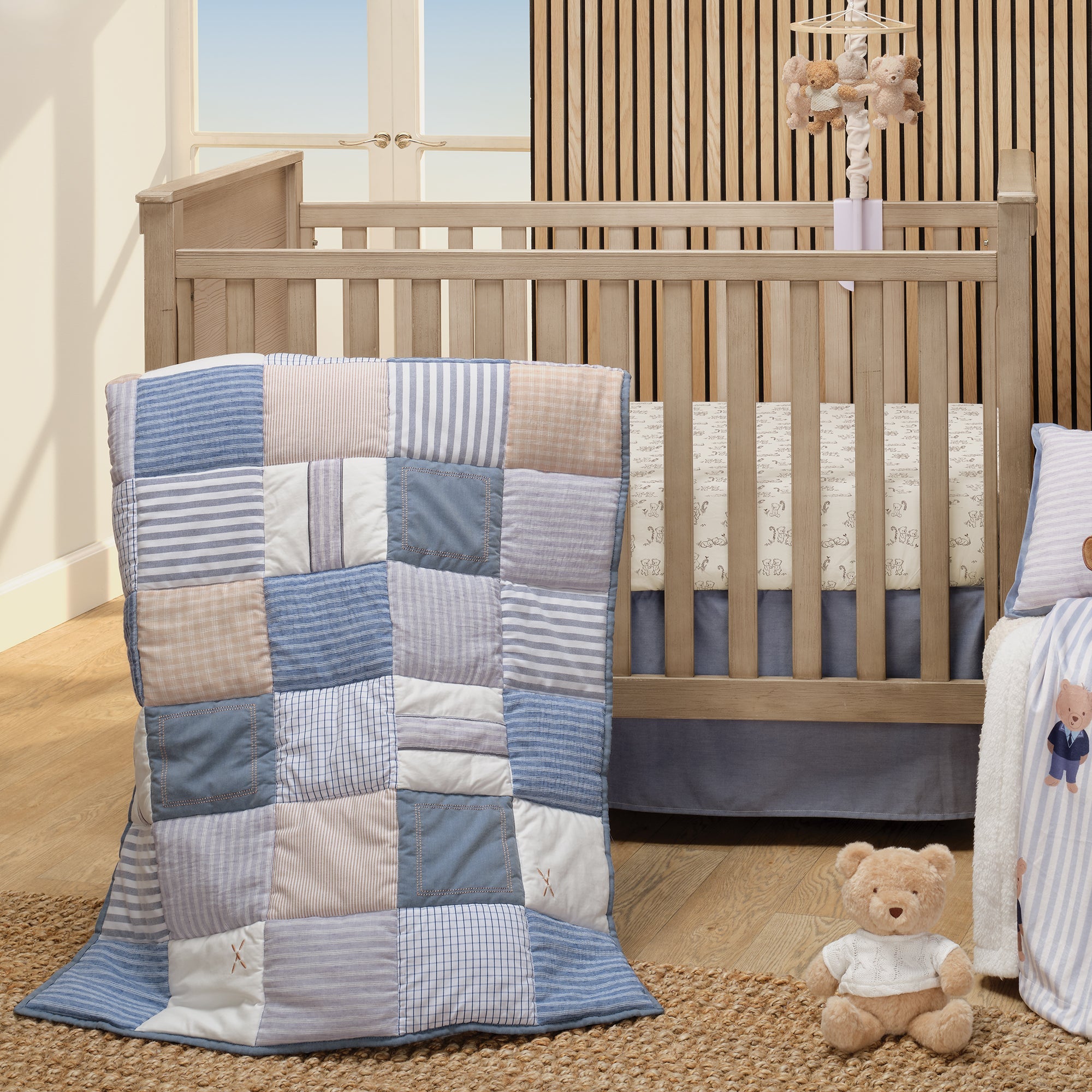 Blue Patchwork Nursery showing Quilt, sheet, skirt, teddy bear, blanket ad mobile.
