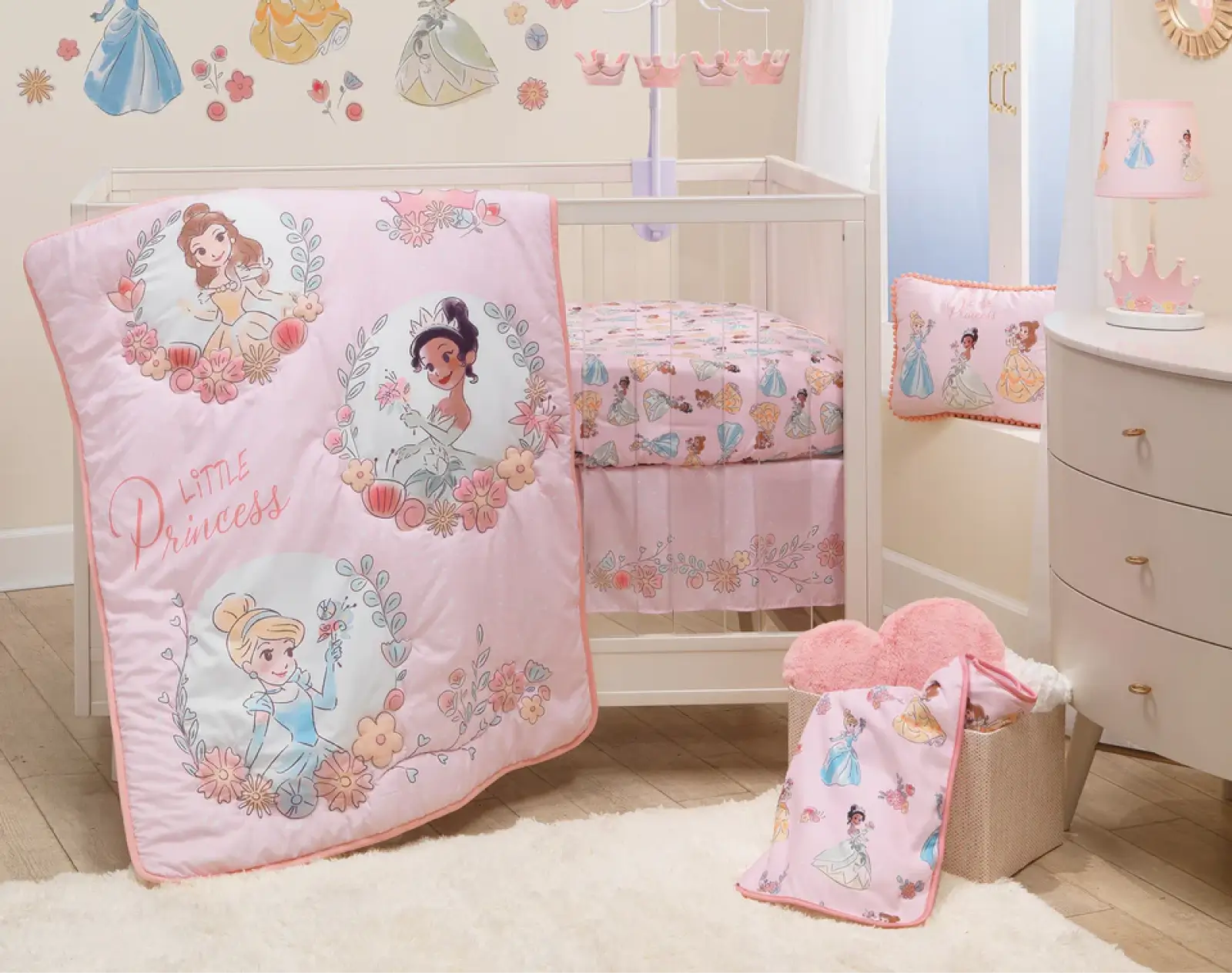Disney Princess baby crib bedding set featuring Belle, Cinderella, and Tiana with pink quilt, matching mobile, and princess wall decals.