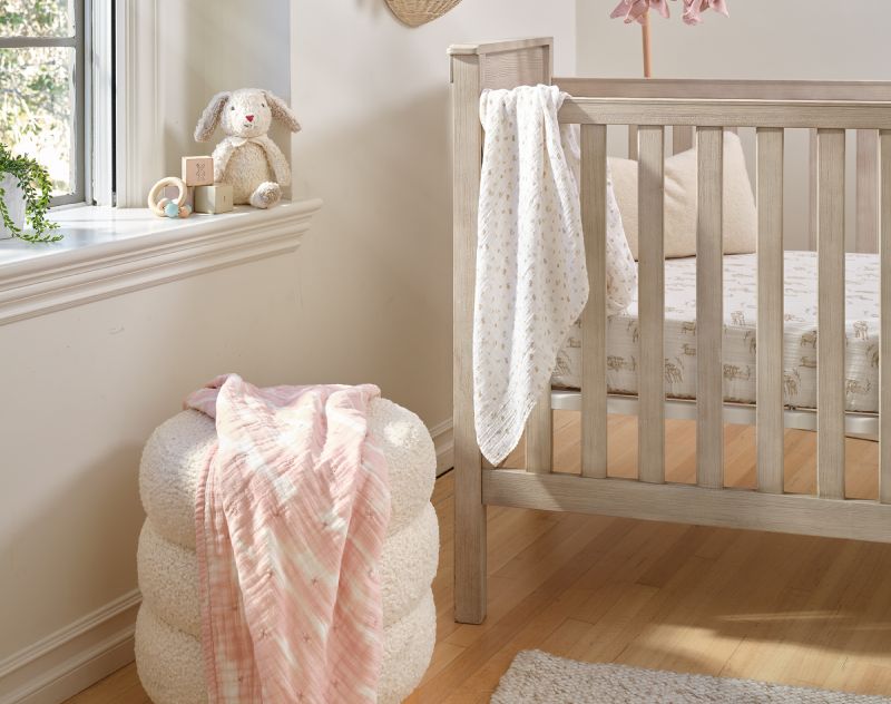Organic baby bedding and blankets in a soft nursery setting.